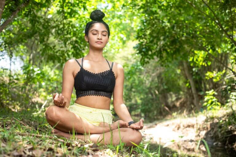 A woman meditating in a serene forest setting, embodying tranquility and mindfulness.